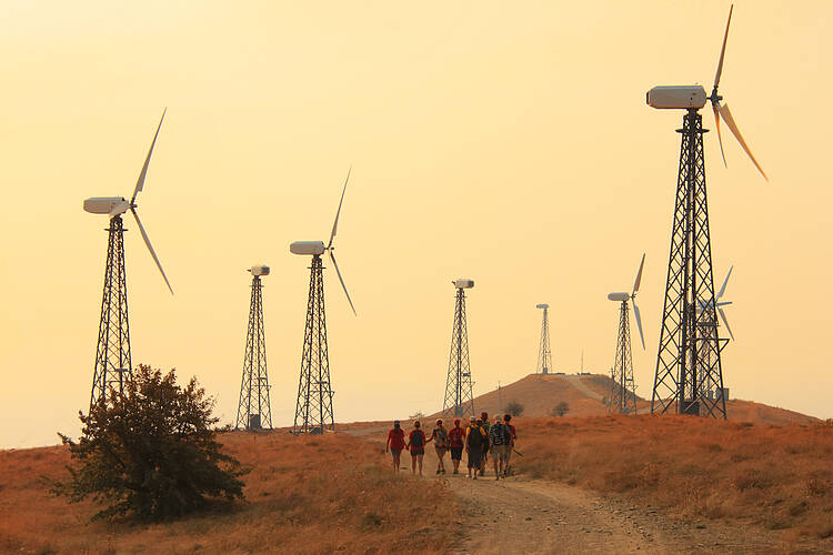 Group of people walking through fields with wind turbines 